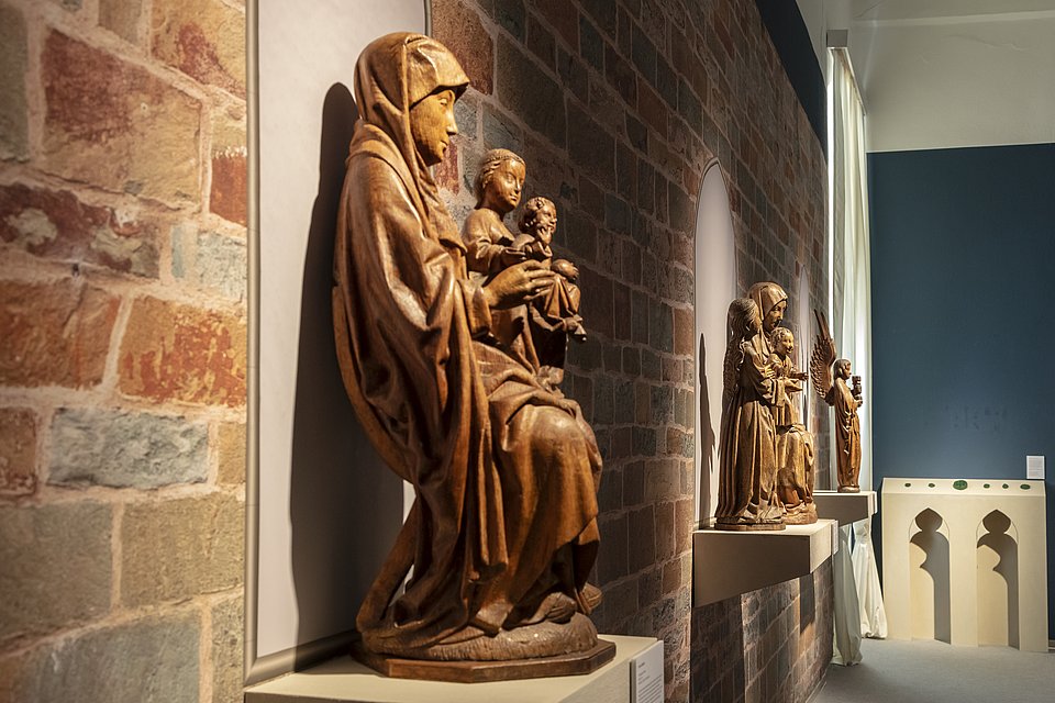 Spätgotische Holzskulpturen vor einer Backsteinwand im Ausstellungsraum