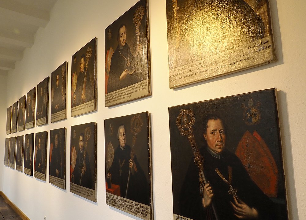 Eine Reihe gerahmter Abtporträts an einer Wand der Ausstellung