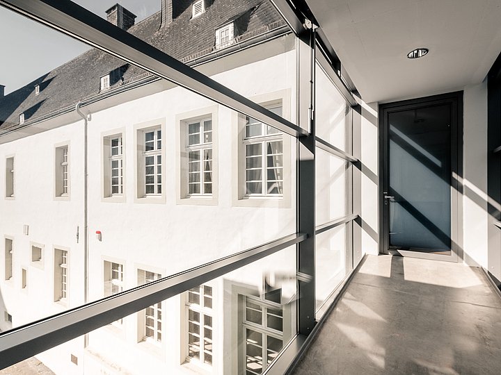 Verglaster Gang mit Blick auf den hellen Innenhof