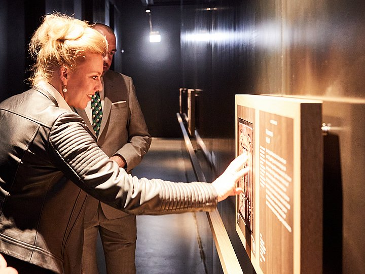 Zwei Gäste betrachten eine beleuchtete Vitrine der Ausstellung