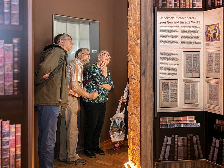 Besucher lesen die Tafel zur Liesborner Buchbinderei