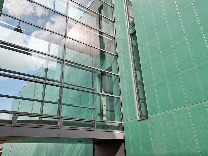 Der gläserne Verbindungsbau mit grün verkleideter Wand