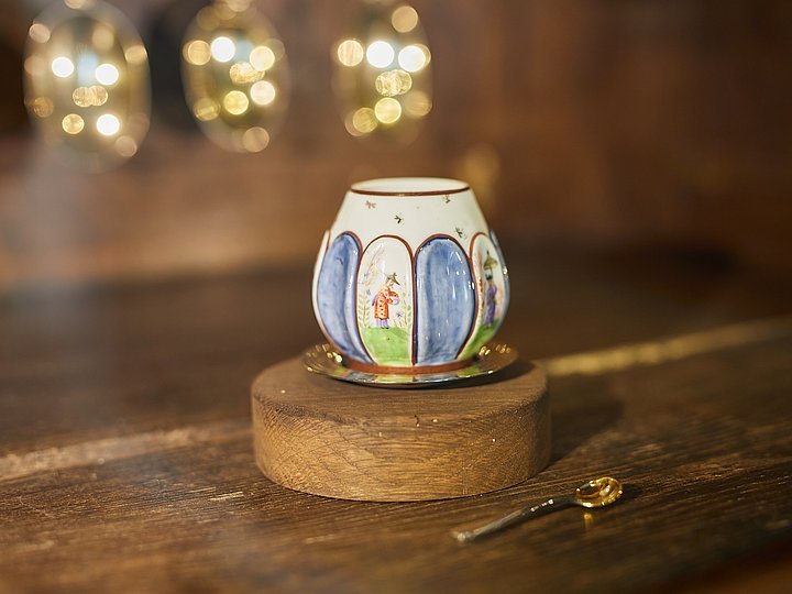 Beleuchtete bemalte Tasse auf einem Holzsockel