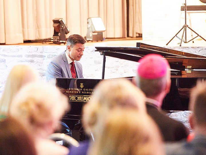 Ein Pianist spielt auf dem Flügel, davor das Publikum