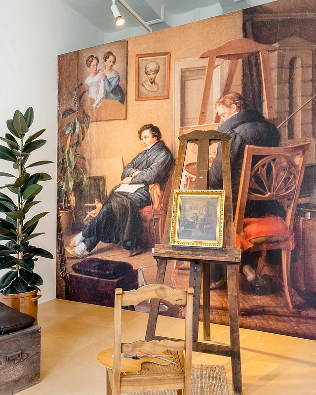 Ausstellungsraum zum 19. Jahrhundert mit Staffelei und gerahmtem Gemälde