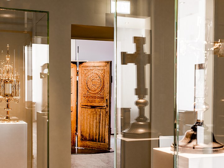 Vitrinen der Kreuzsammlung mit Kelch, Kreuz und geschnitzter Tür