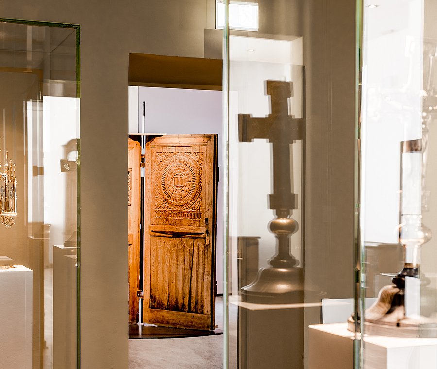 Vitrinen der Kreuzsammlung mit Kelch, Kreuz und geschnitzter Tür