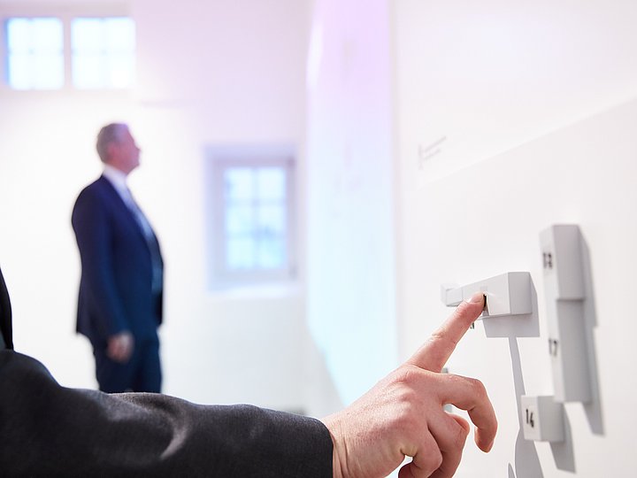 Eine Hand berührt die tastbaren Elemente an der Wand der Ausstellung