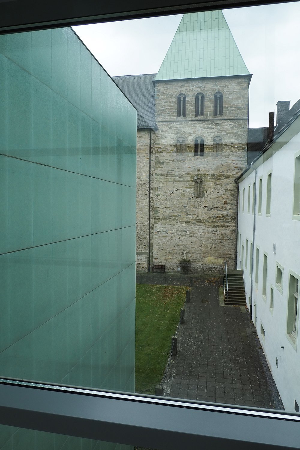 Blick durch eine Glaswand des Museums auf den romanischen Turm der Klosterkirche